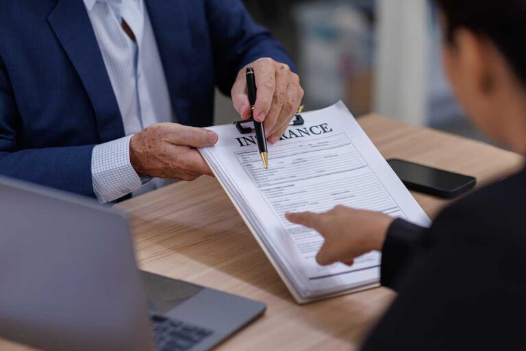 A person taking photos of two vehicles after a minor road collision, with documents and a phone visible in hand.