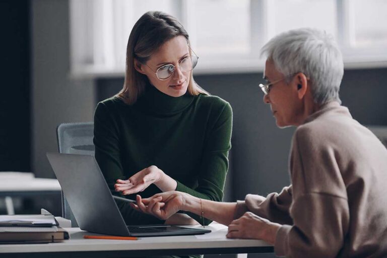 A family of four sits together at a kitchen table reviewing paperwork and discussing finances.