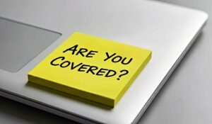 Homeowner reviewing insurance renewal papers beside a calculator and household records